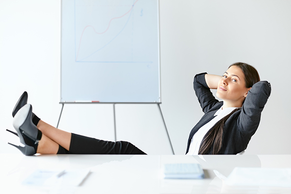 Portrait of relaxed business woman sitting with legs on desk in