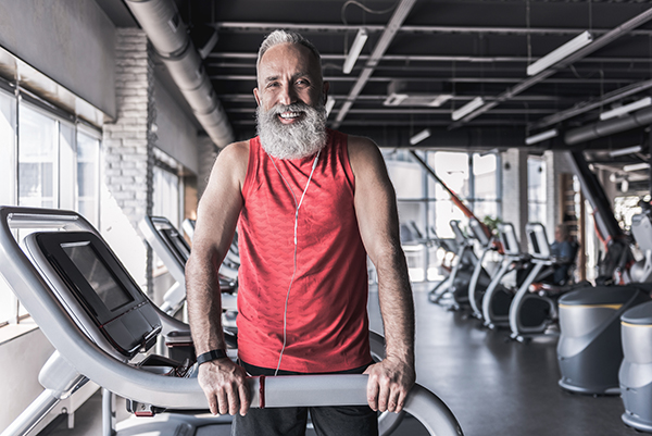 Joyful old stylish male is spending time in athletic center
