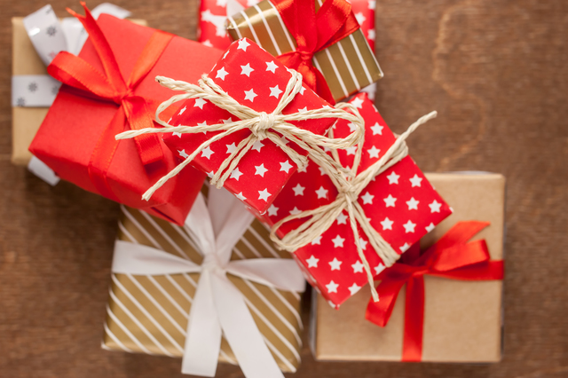 pile of different gifts with wrapping on wooden background