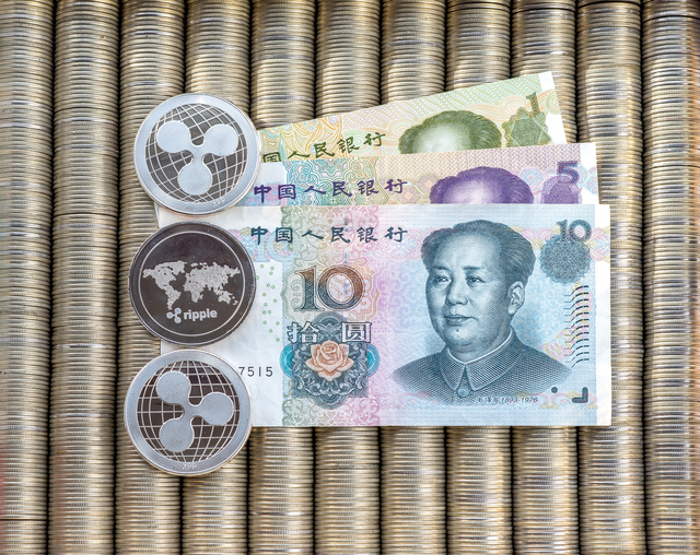 Silver crypto coins Ripple XRP, paper denominations Chinese yuan. Metal coins are laid out in a smooth background to each other, close-up view from top, crypto currency exchange of money.