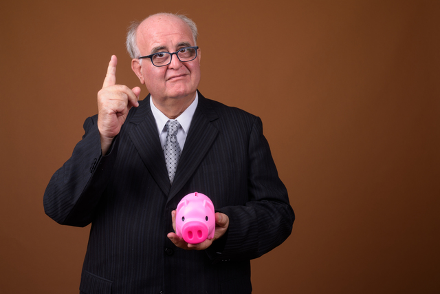 Portrait of overweight senior businessman holding piggy bank